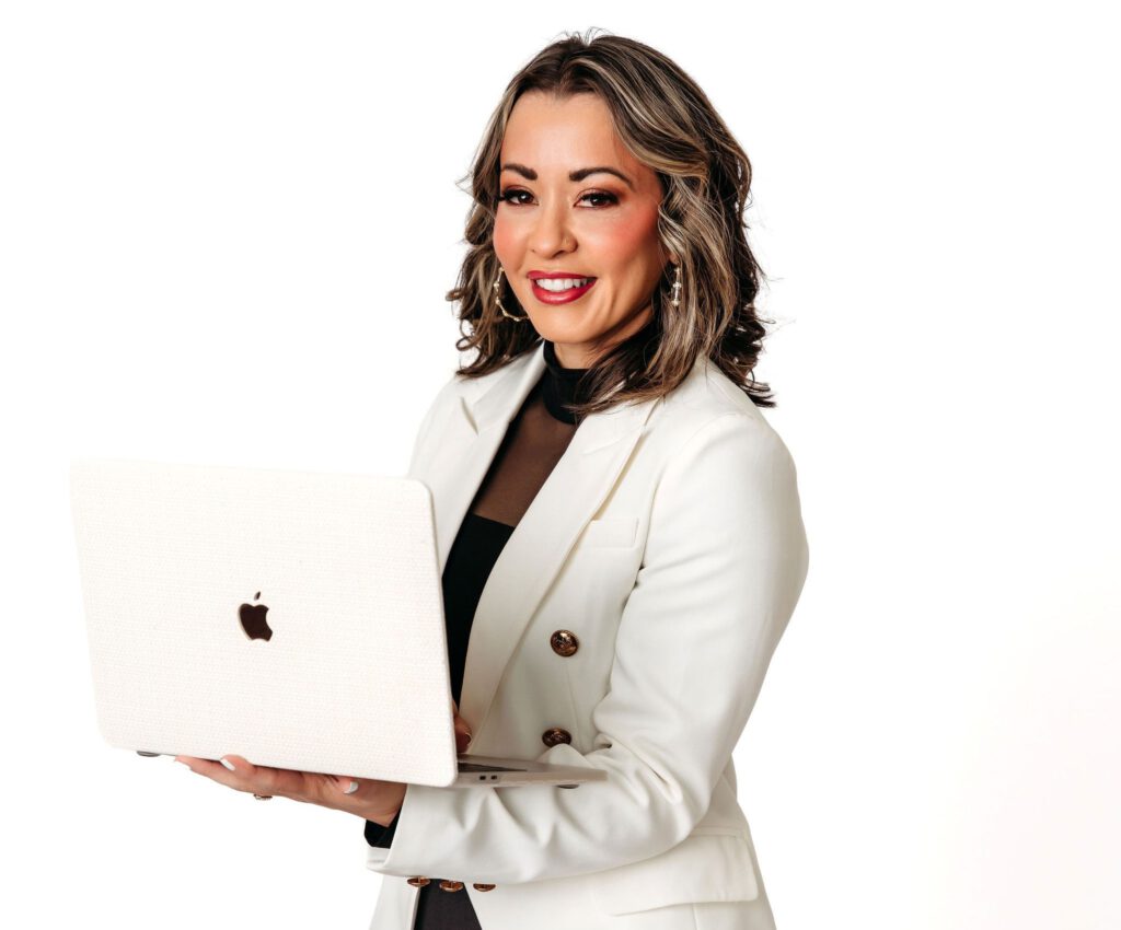 Lexi Yoo NP in a white blazer holding an open laptop in a studio portrait