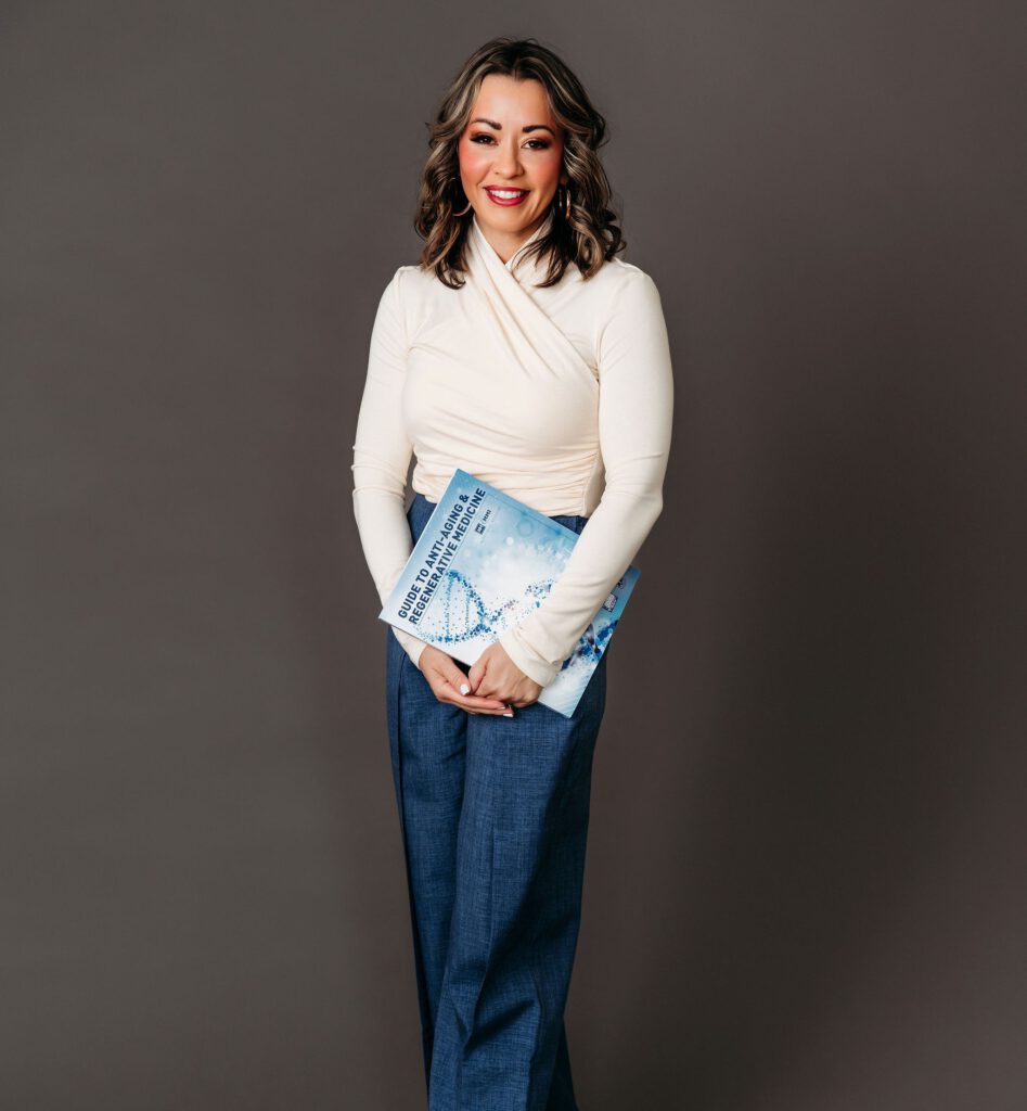 Lexi Yoo NP holding the Guide to Anti-Aging and Regenerative Medicine textbook in a studio portrait
