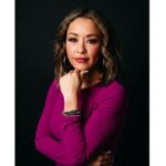 Lexi Yoo, nurse practitioner - Magenta long-sleeve top, chin resting on fist, black background - moody general portrait